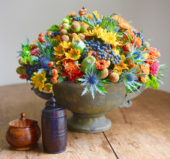 Mixed arrangement of mums, dahlias, blue viburnum berries, blue thistle, poppy pods and rose hips.